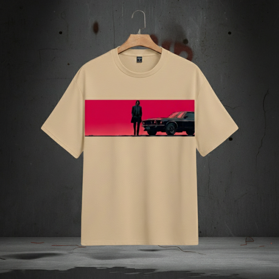 Beige t-shirt with a graphic of a person and car on a red background, hanging against a dark wall.
