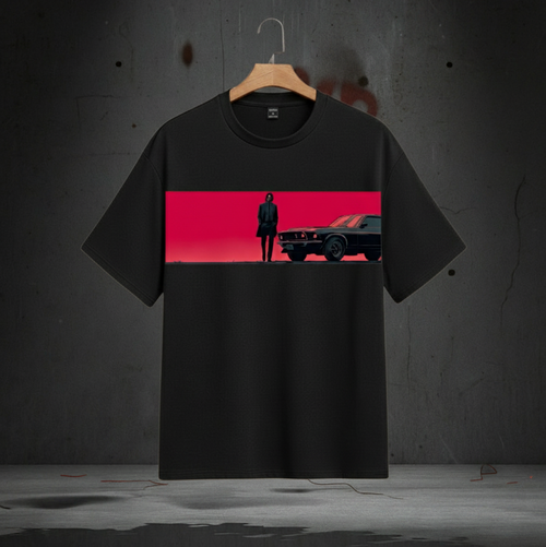 Black t-shirt with a graphic design of a man and car on a red background, hanging against a dark wall.